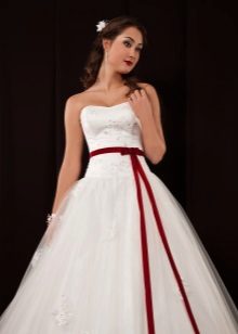 A puffy wedding dress with a low waist and a red belt