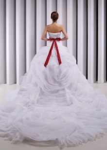 A magnificent wedding dress with a train and a red bow