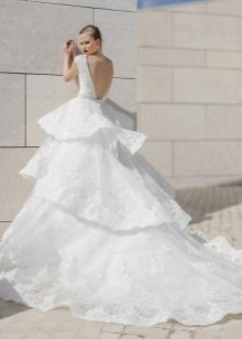 A puffy wedding dress with a tiered skirt and a train