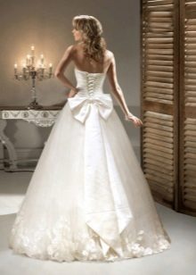 A wedding dress with a bow and flowers in tone