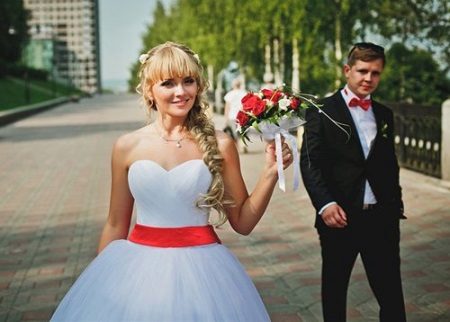 Wedding dress with a red belt and a red bouquet